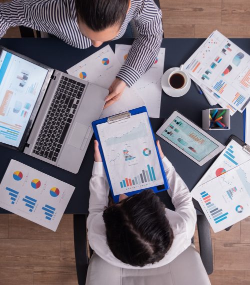 top-viewtop-view-manager-employee-doing-teamwork-business-office-looking-charts-laptop-display (1)